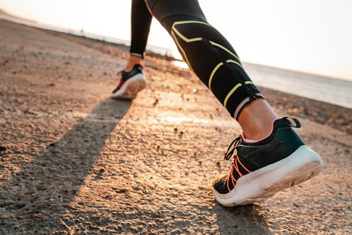 Sports and running. A woman runs along the sea. Close-up of feet in sneakers