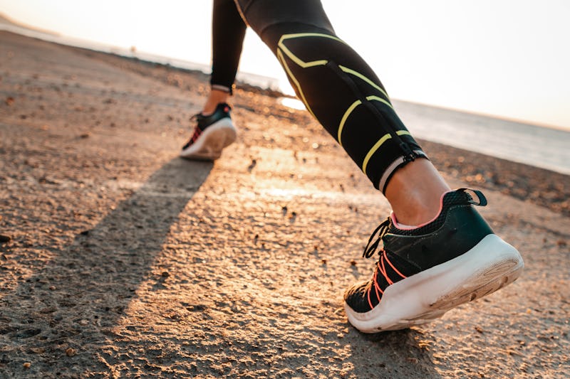 Sports and running. A woman runs along the sea. Close-up of feet in sneakers