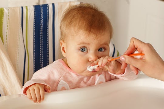 baby girl learning to use a spoon