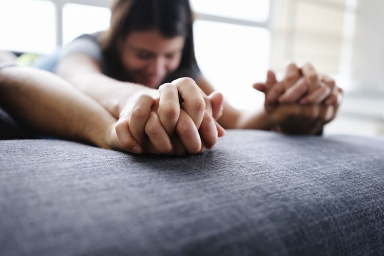 Young hispanic couple lying on sofa, embracing and holding hands during foreplay. Focus on foregroun...