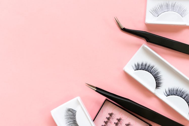 Tools for eyelash extension on trendy pastel pink background. False eyelashes and tweezers. Beauty s...