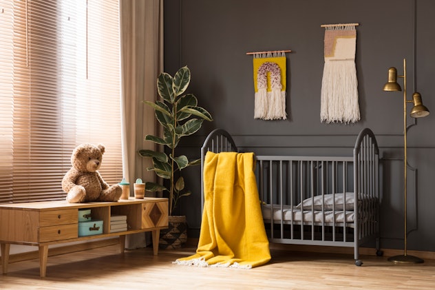 a rustic nursery with gray crib and yellow blanket