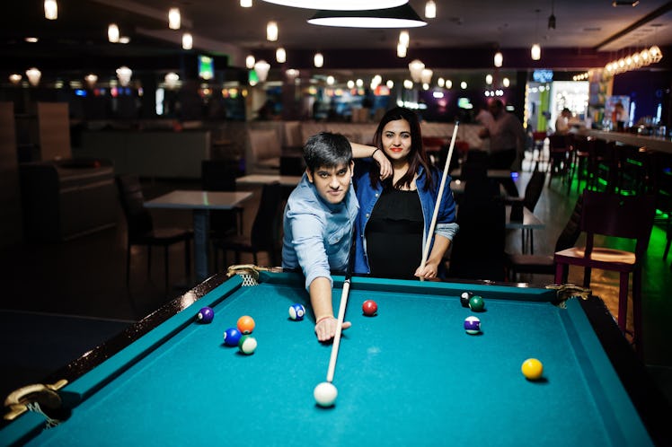 A couple plays pool at a local bar while on a hometown date.