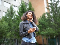 Beautiful young African-American woman listening to music outdoors