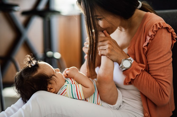 A baby girl in a rainbow-striped shirt lays in her new aunt's lap and giggles.