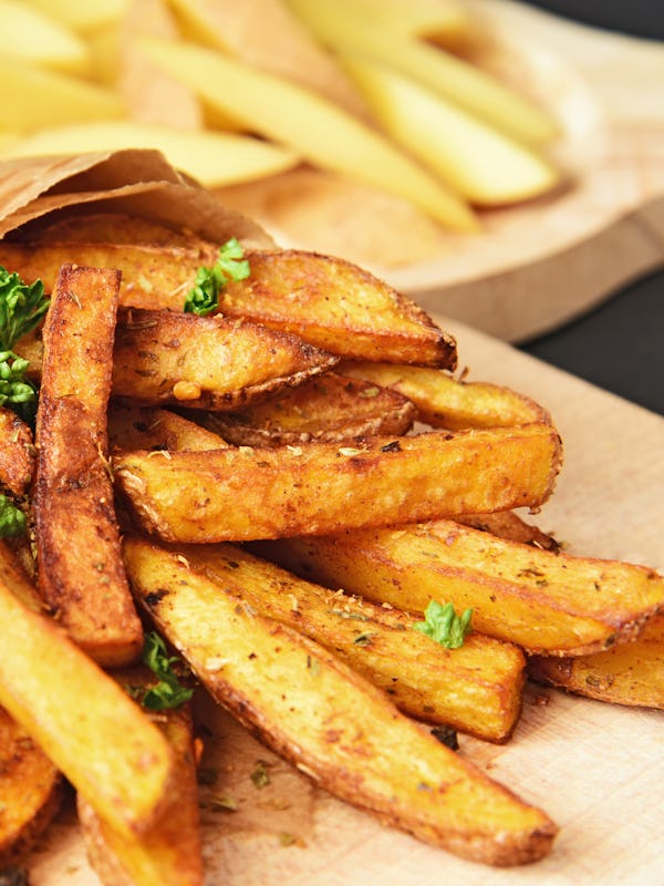 Homemade Crispy Seasoned French Fries.
French fries  with spicy seasoning in brown paper bag on wood...