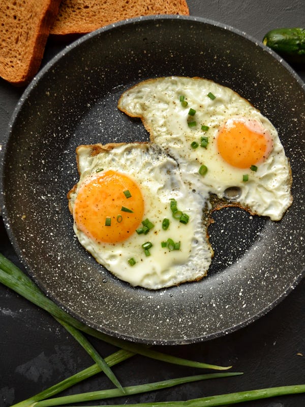 Tasty breakfast. Food on the table. Food on a dark concrete background. Fried eggs in a pan. Eggs, g...