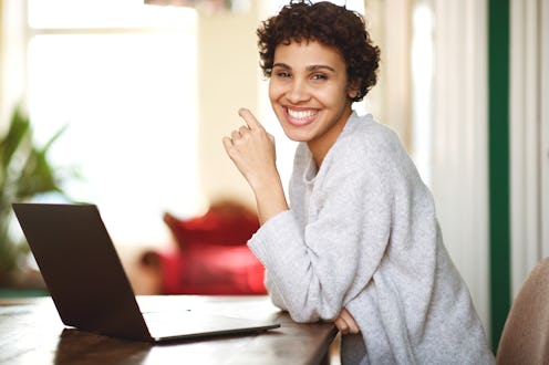 Portrait of happy african american woman with laptop computer at home