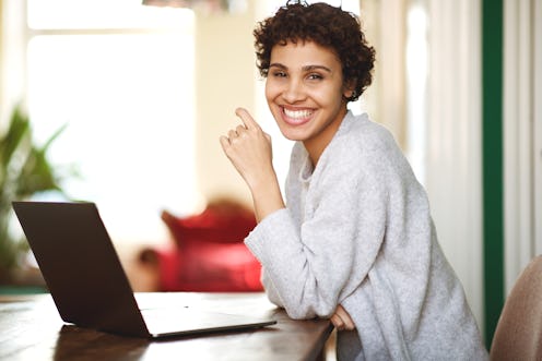 Portrait of happy african american woman with laptop computer at home
