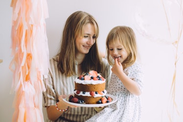 An aunt celebrates her niece's birthday with her with light pink decorations and a berry-covered cak...