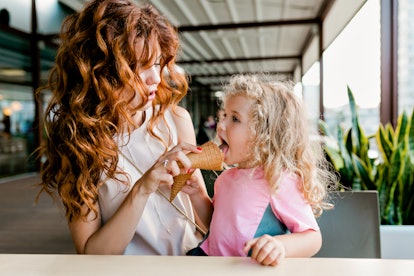 A young woman and her niece eat ice cream cones in a café on her niece's birthday.
