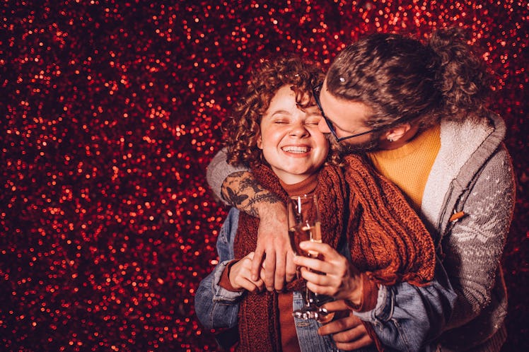 Young couple drinking champagne in front of the red glitter wall. New year party