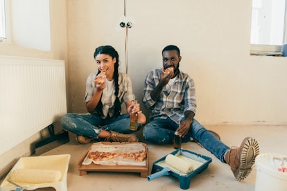 A couple enjoys their favorite pizza on the floor of their new apartment while it's being redone.
