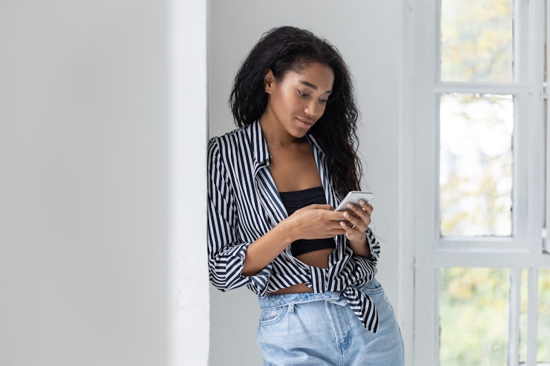 Cute Afro American pretty woman texting on mobile phone. Leisure time concept