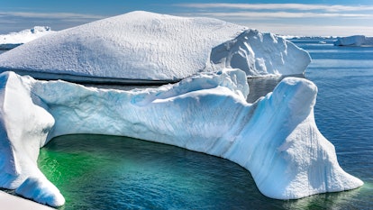 Antarctic iceberg and majestic landscape, sunny day, green lagoon