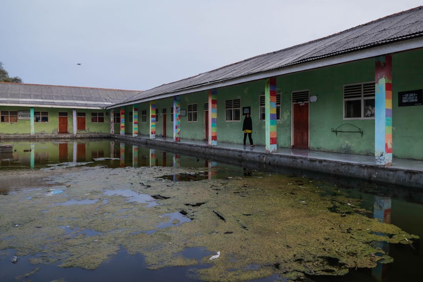 A villager walks along a flooded school yard at Pantai Bahagia village in Bekasi, West Java, Indones...