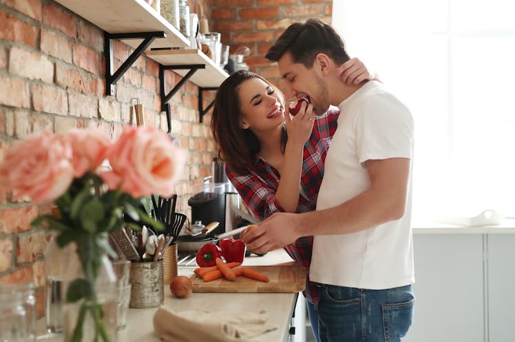 A happy couple prepares dinner in a bright kitchen on Valentine's Day.