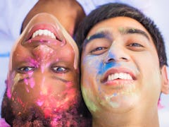 Close-up the young happy couple lying face to face with paints on their faces and smiling