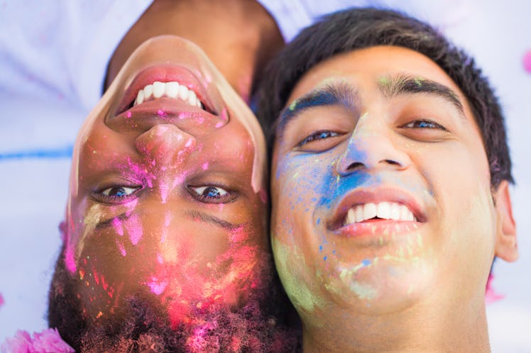Close-up the young happy couple lying face to face with paints on their faces and smiling