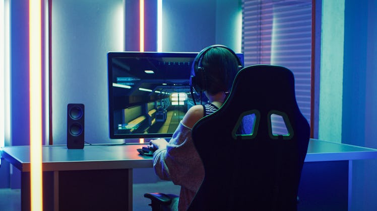 Beautiful Professional Gamer Girl Playing in First-Person Shooter Online Video Game on Personal Comp...