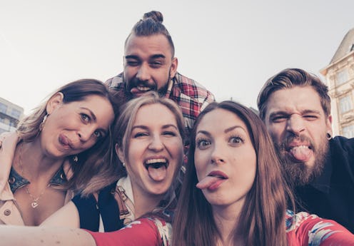 crazy best friends take a selfie downtown city environment poking out tongues making silly faces to ...
