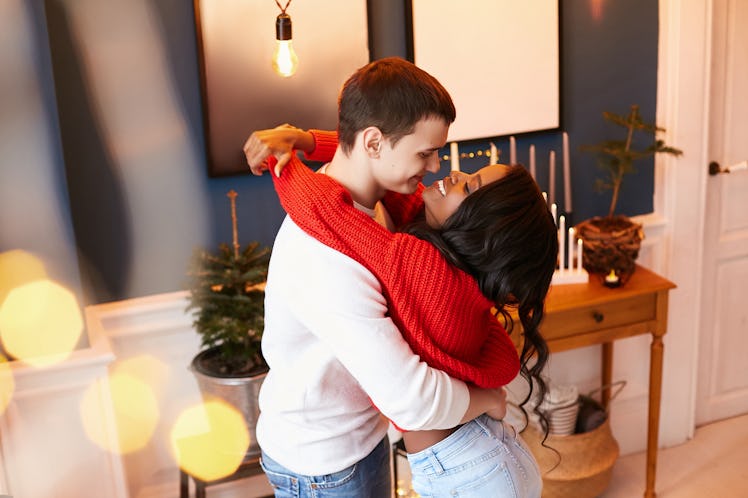 A happy couple embraces in a bright living room.