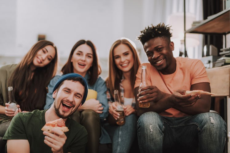 A group of friends eats pizza and drinks beer while watching the 2020 Super Bowl.