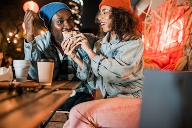 A trendy couple in beanie caps enjoy each other's company at a coffee shop.