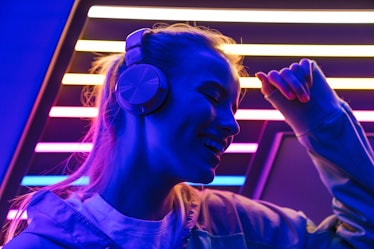 Image closeup of beautiful young caucasian woman listening to music with headphones over multicolore...