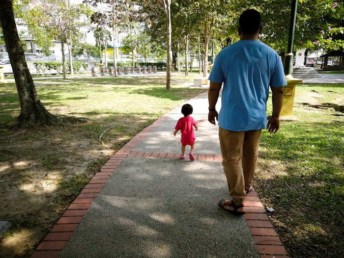 Asian father and baby toddler daughter walking in the park.