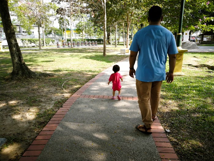 Asian father and baby toddler daughter walking in the park.
