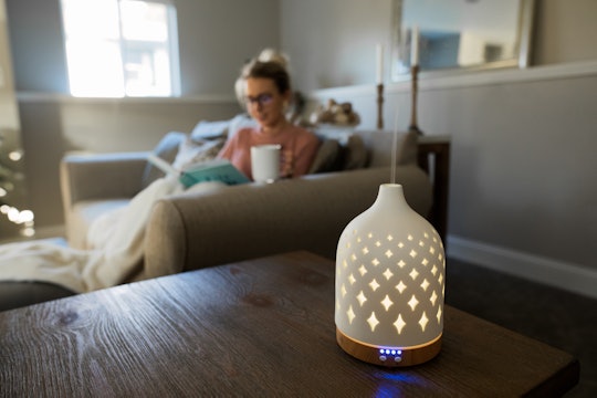 Essential oil diffuser with a young woman relaxing in the background