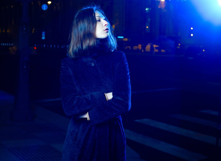 Fashion portrait girl in the night city and lights of street lamps. in the coat. illuminated by a bl...
