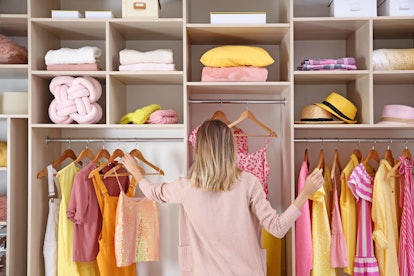 Woman choosing clothes from large wardrobe closet