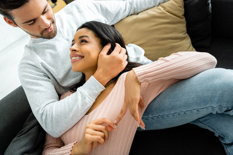 african american woman and handsome man smiling and hugging in apartment 
