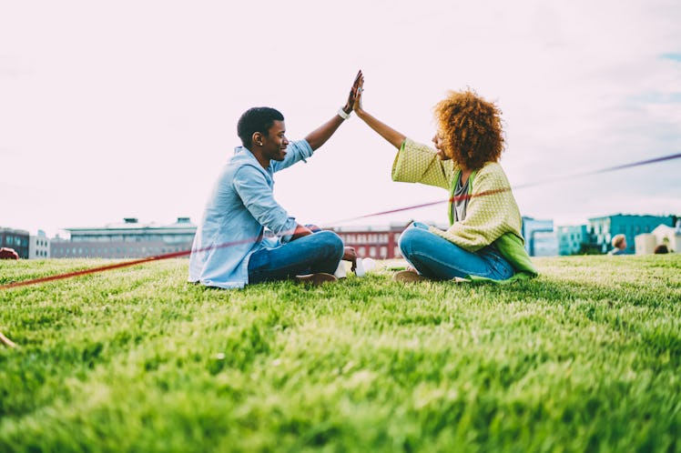 A couple smiles and gives each other a high five on a football field.