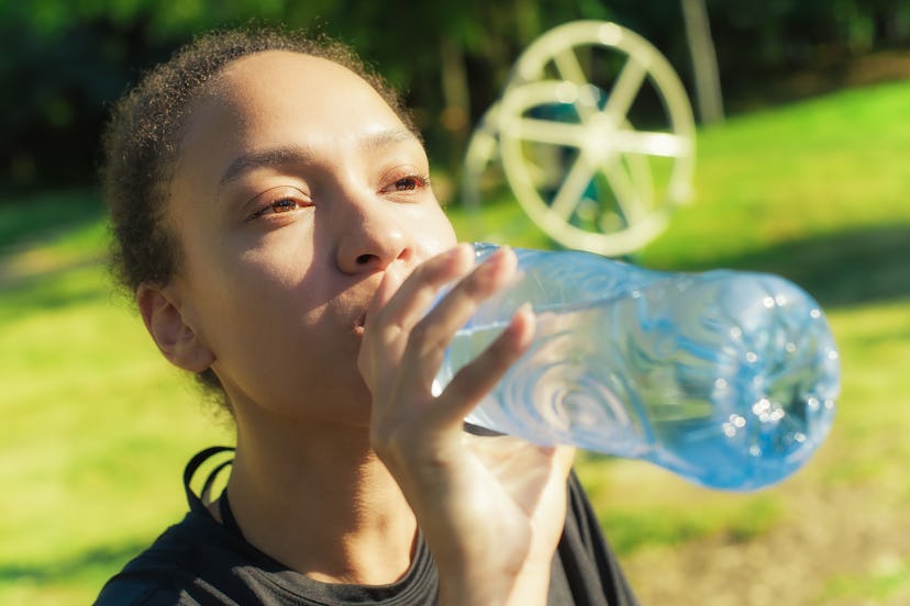 Woman drinking water from bottle after fitness sport exercise
