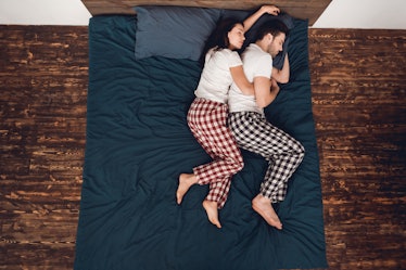 Top view. Young couple in pajamas sleeps close together on bed at home. Sleep poses. Young couple of...