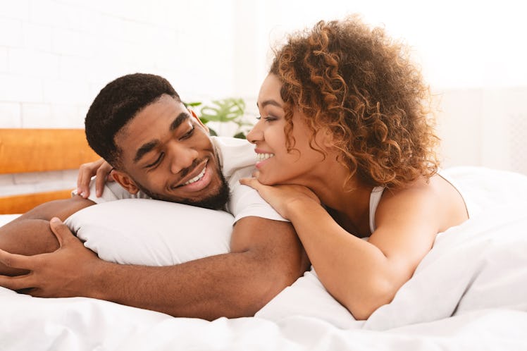 Loving black couple relaxing in bed at home, enjoying sweet good morning together