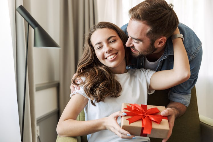 A happy couple exchanges a present at home.