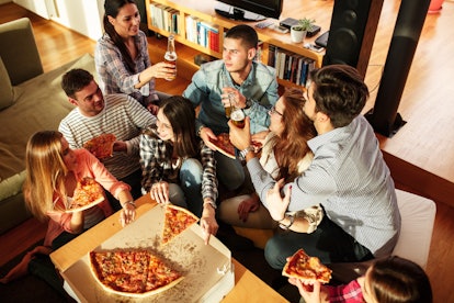 A group of friends enjoy pizza and beer at home.