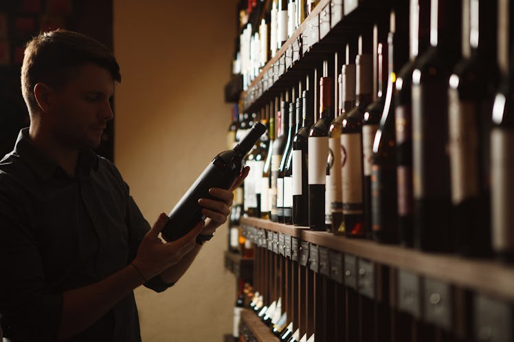 man choosing bottle of wine from shelves