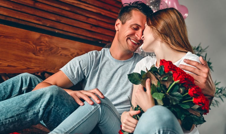 Celebrating Saint Valentine's Day. A man gave a woman a  red roses. A couple is sitting on the bed w...