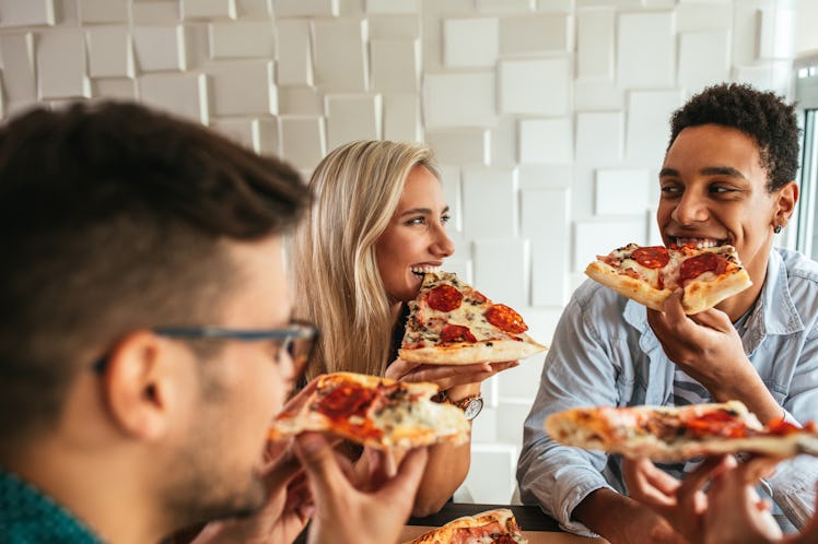 A group of friends sits at a table and enjoys a pizza.