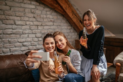 Three beautiful female friends taking a selfie in the apartment