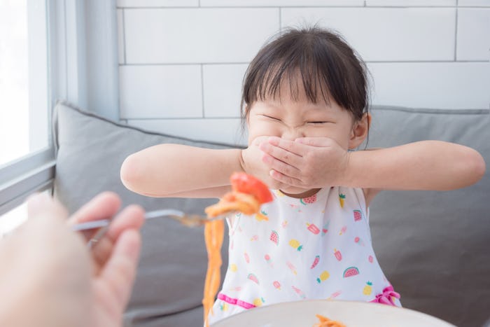 a little girl refusing to eat spaghetti