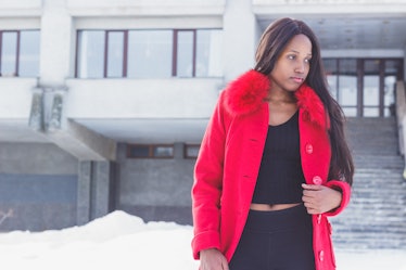 Winter life: Young African woman in a red coat, black pants and sweater.