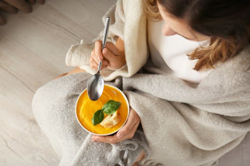 Woman eating tasty cream soup at home