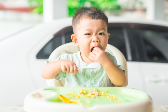 a toddler boy eating eggs in his high chair