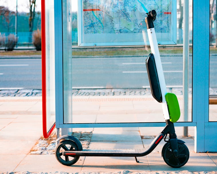 Electric scooter stands near public bus stop. Electric scooters stand along the streets of downtown....